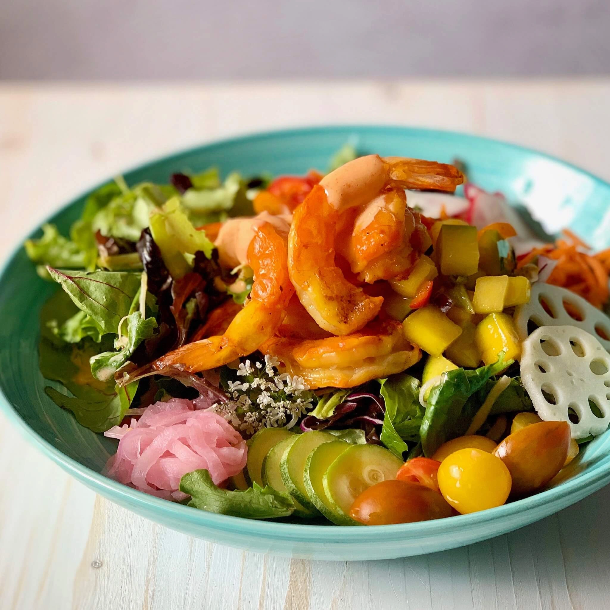 A bowl of salad with shrimp and vegetables in it.