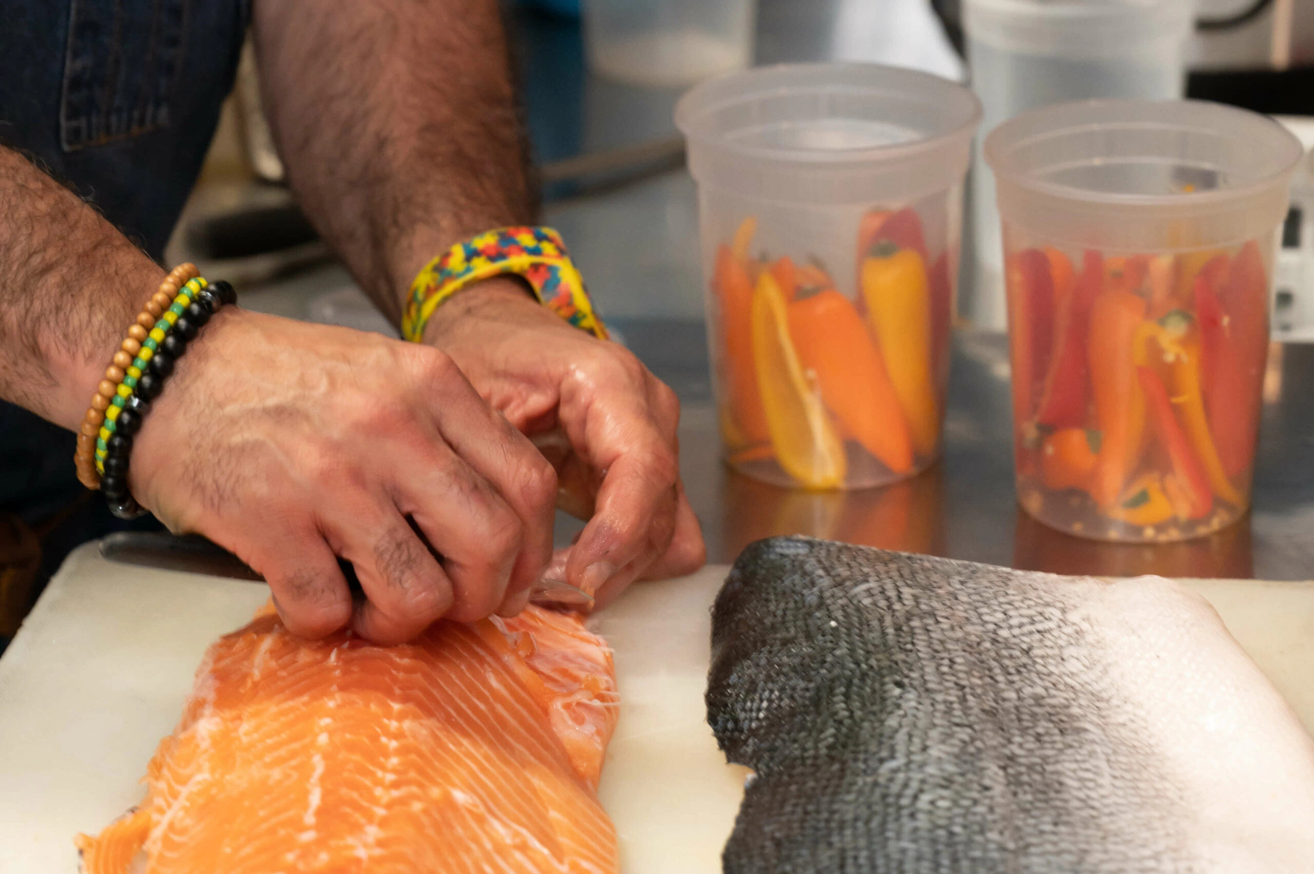 A chef meticulously preparing a salmon by skillfully removing its skin and deboning the fish